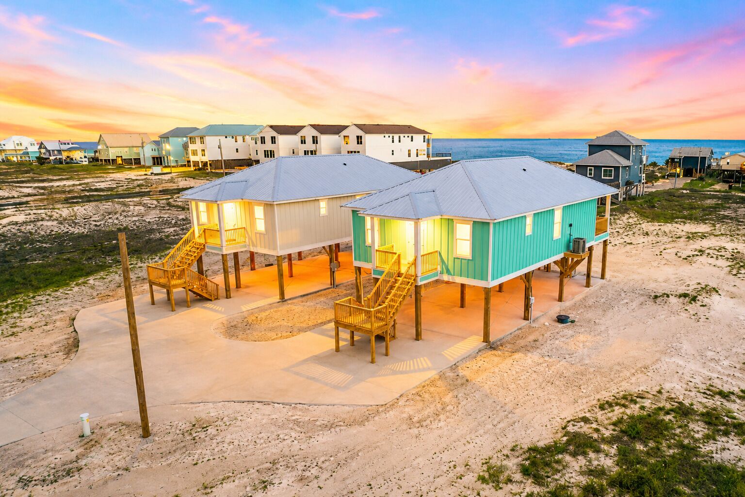 Una propiedad frente al mar con casas elevadas, una playa de arena y vista al océano.