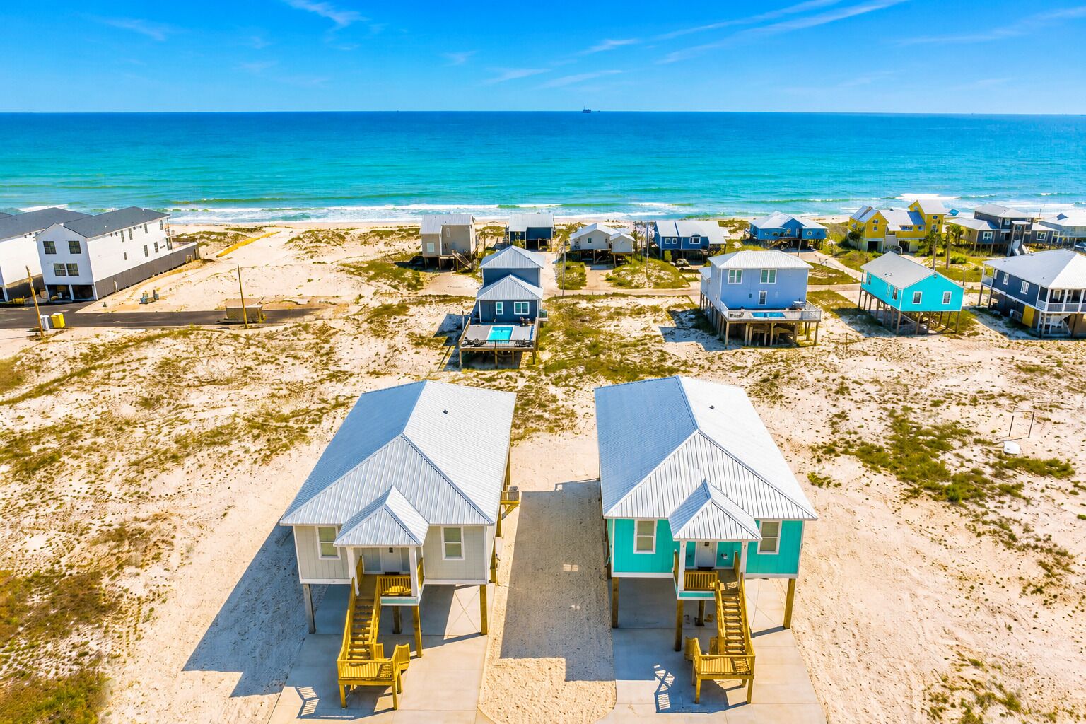 A beachfront property with multiple houses, some elevated on stilts, and a clear view of the ocean.