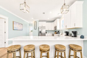 A modern kitchen with white cabinets, a large island, and bar stools. - "How You Dune"
  Serene 3-bedroom house with GULF views in Fort Morgan! (Gulf Shores)