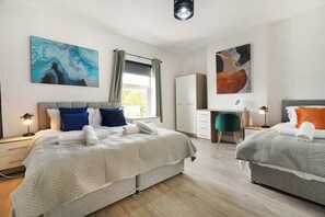 A modern hotel room with two beds, a desk, and artwork on the walls. - Cozy 2BR Home Sleeps 5 with WiFi by Stay With Us (Platt Bridge)