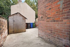 Une ruelle étroite avec un abri en bois et un mur de briques.