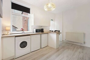 Eine moderne Küche mit Waschmaschine, Mikrowelle und Essbereich mit Tisch und Stühlen.