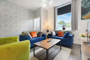 A modern living room with two sofas, a coffee table, and a large window offering a view. - Cozy 2BR Home Sleeps 5 with WiFi by Stay With Us (Platt Bridge)