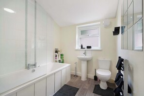 A modern bathroom with a bathtub, toilet, and sink. - Cozy 2BR Home Sleeps 5 with WiFi by Stay With Us (Platt Bridge)