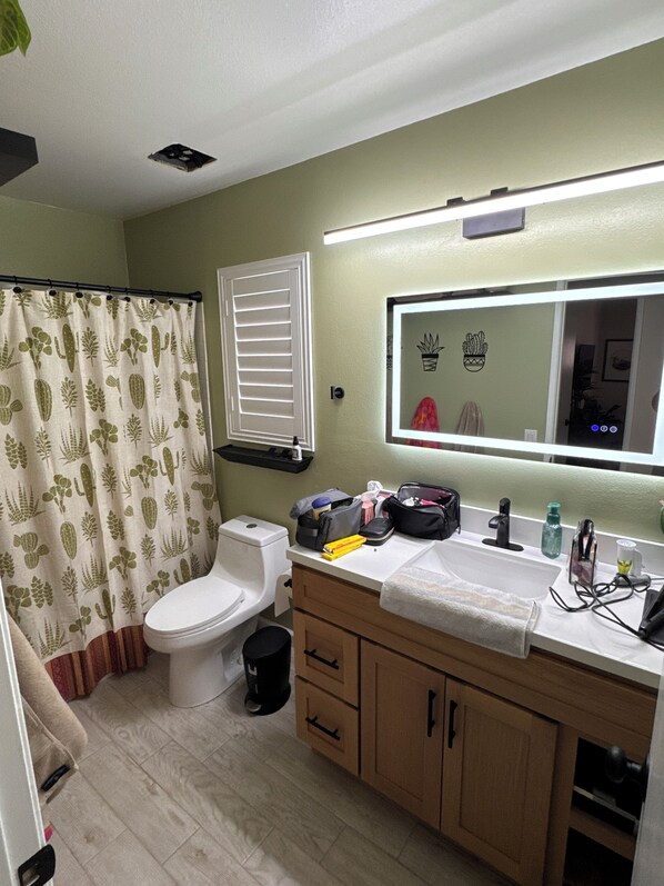 A bathroom with a toilet, sink, mirror, and shower curtain.