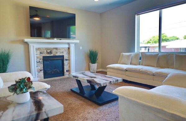 Una sala de estar con chimenea, un sofá, una mesa de centro y un televisor sobre la chimenea.