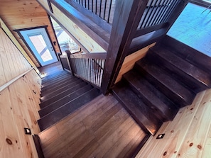 Un escalier en bois, doté d’une rampe, mène à un espace extérieur d’où l’on peut admirer le ciel.