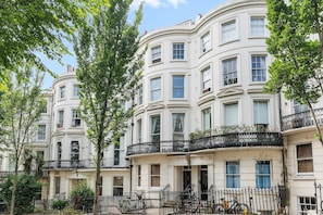 A row of white, multi-story buildings with balconies, surrounded by trees. - Coastal Calm By My Getaways (Brighton)
