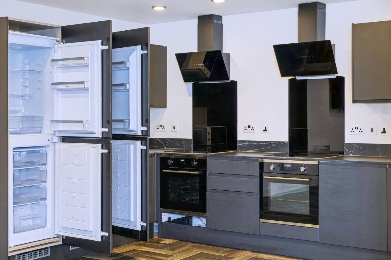 Une cuisine moderne équipée d’un four encastré, d’un four à micro-ondes et d’un réfrigérateur à deux portes.