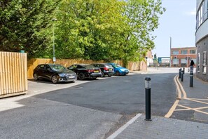 A parking lot with multiple cars and a pedestrian walking on the sidewalk. - Brand New Spacious Studio in Beeston (Beeston)