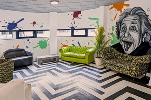A room with a green sofa, a patterned armchair, a potted plant, and a large abstract painting on the wall. - Brand New Spacious Studio in Beeston (Beeston)