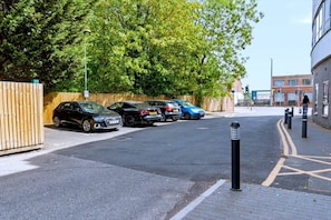 Ein Parkplatz mit mehreren Autos, einem Holzzaun und einem Gebäude mit Backsteinfassade.