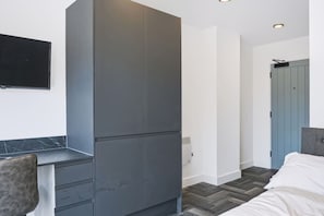 A modern bedroom with a bed, a desk, and a wardrobe. - Brand New Spacious Studio in Beeston (Beeston)