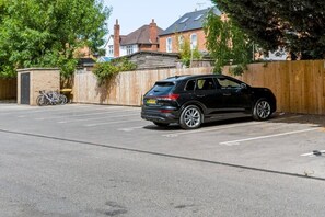 A black SUV parked in a parking lot with a wooden fence and a bicycle in the background. - Brand New Spacious Studio in Beeston (Beeston)