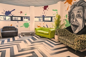 A room with a green sofa, a black leather sofa, a bench, and a large abstract painting on the wall. - Brand New Spacious Studio in Beeston (Beeston)