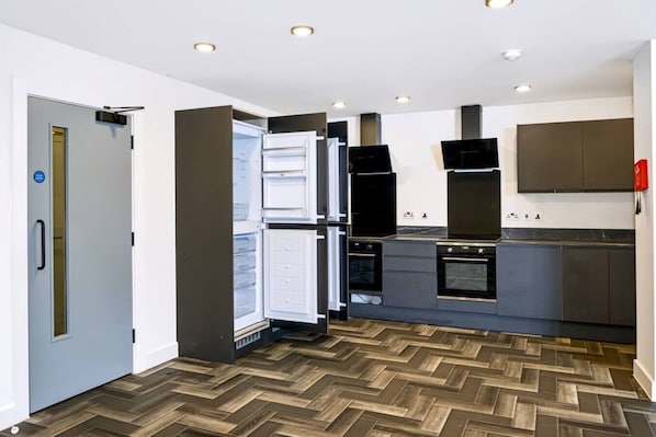 Een moderne keuken met een inbouwkoelkast, oven en magnetron.