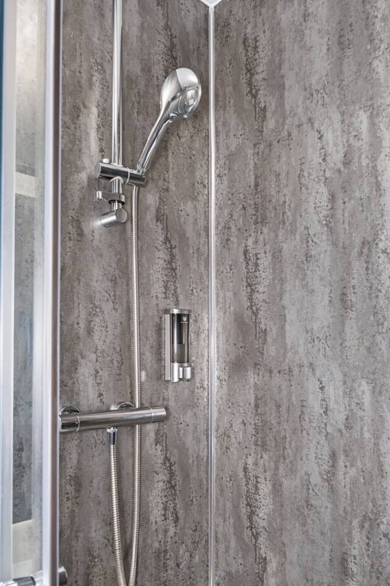 A shower enclosure with a handheld showerhead, a handheld shower attachment, and a flexible hose.