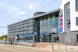 A modern building with large glass windows and a sign indicating tramway access. - Brand New Spacious Studio in Beeston (Beeston)