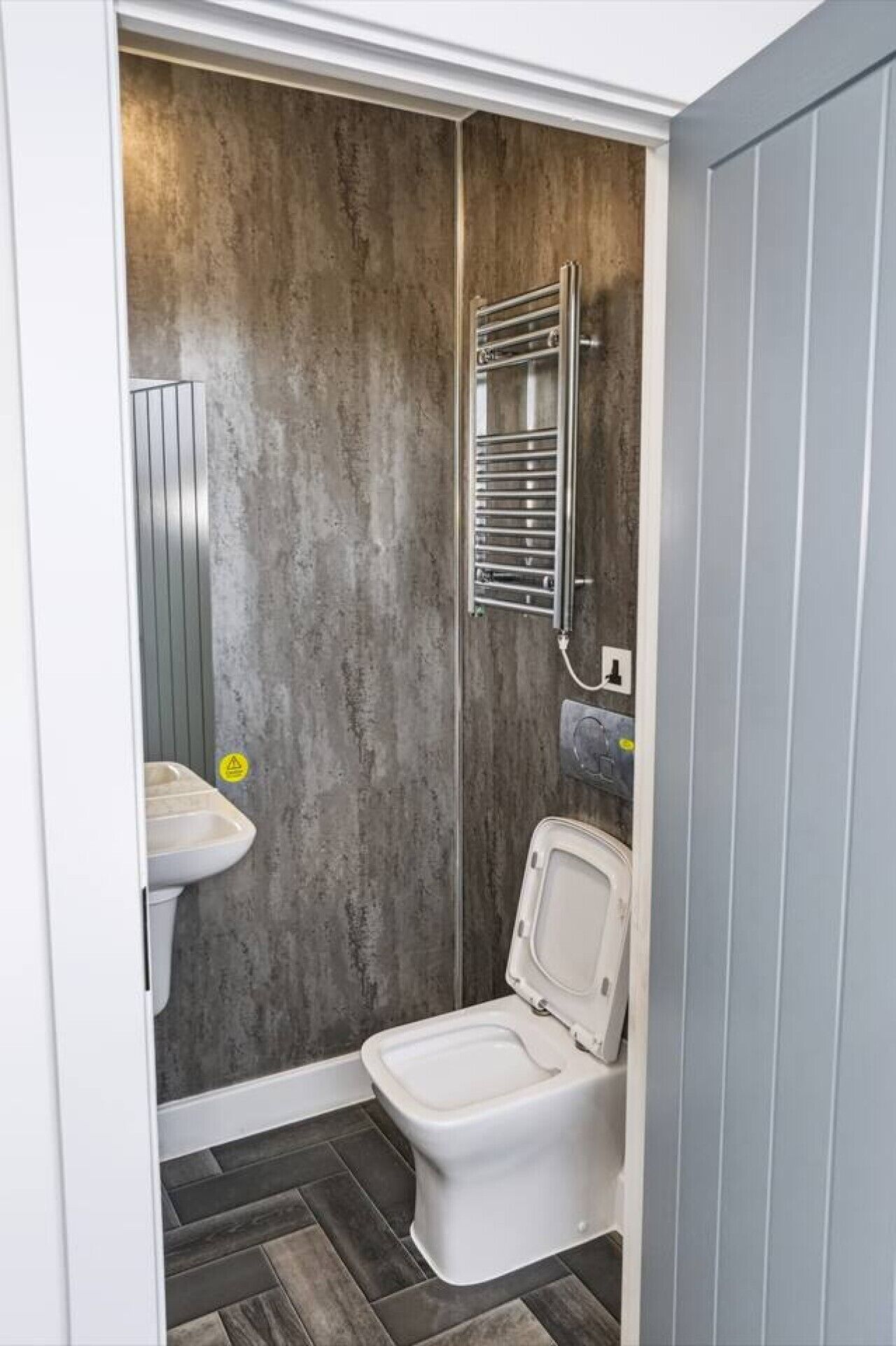 Casa de banho compacta com sanita, lavatório e um porta-toalhas.
