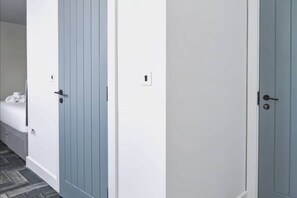 Ein Flur mit drei Türen, eine weiße und zwei blaue, der zu Zimmern führt.