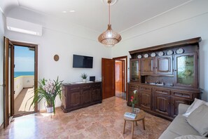 A spacious living area with a large wooden cabinet, a flat-screen TV, and a potted plant. - Casa Olga, with a view of the sea (Praiano)