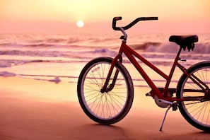 A bicycle on a beach with waves in the background.
