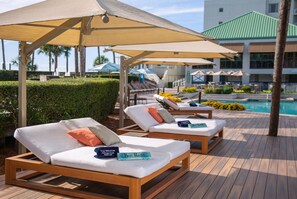 A poolside area with sun loungers, umbrellas, and a pool.