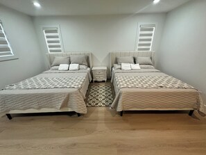 A bedroom with two beds, a nightstand, and a patterned rug. - 5 bedroom house sleeps 12 people (Surrey)