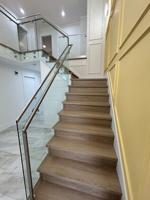 Una escalera con barandillas de vidrio y escalones de madera.