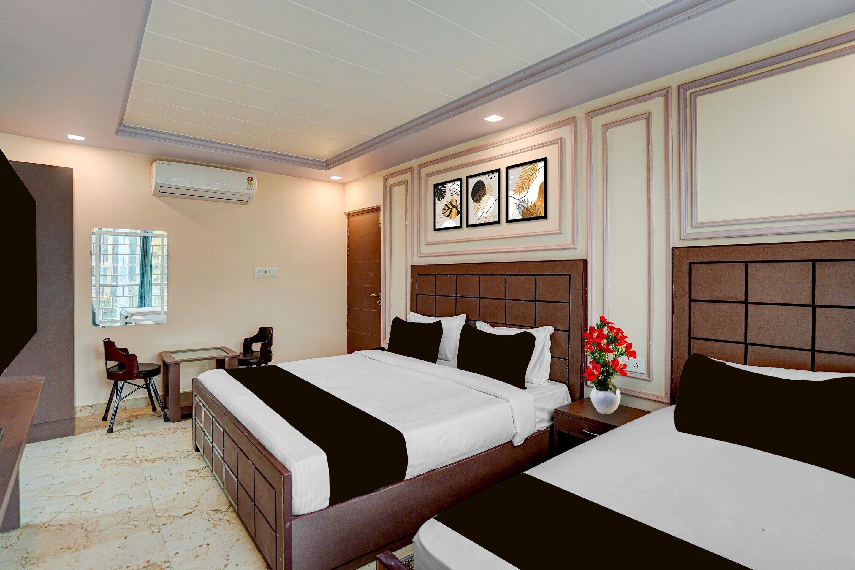 A hotel room with two beds, a desk, a chair, an air conditioning unit, and a window.