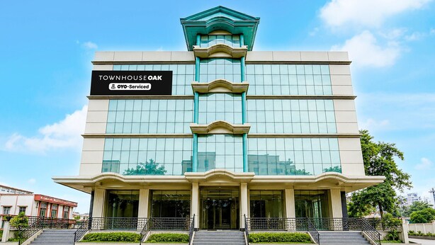 A multi-story building with a sign reading 'TOWNHOUSE OAK' and 'YO-Service'. - Premium Family Suite With Balcony Mauji's (Prayagraj)