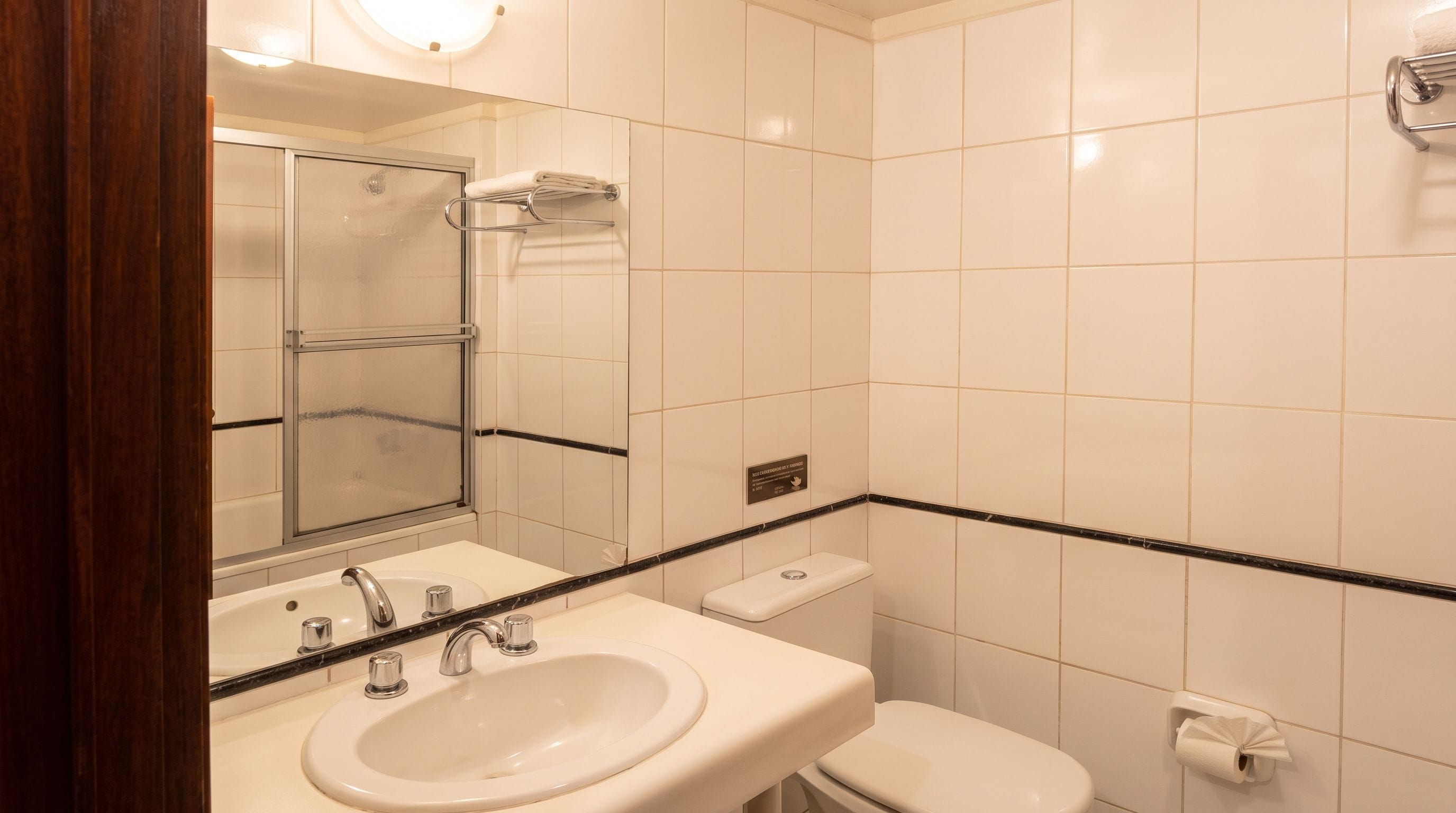 A bathroom with a sink, mirror, toilet, and a towel rack.