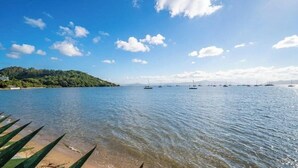 A calm lake with boats, clear skies, and a forested hill in the background. - Beautiful Beachfront House Santo Antonio Cda1647 (Florianópolis)