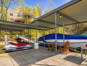 Ein überdachter Bootssteg mit einem Yamaha Jetski, Stühlen und einem Haus im Hintergrund.