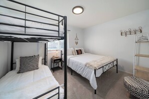 A dorm-style room with bunk beds, a bedside table, a lamp, and a hanging light fixture. - private pool + spa + game room + near Coachella | Family & Group Friendly (Indio)
