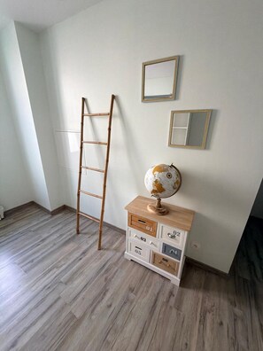 A room with a wooden ladder leaning against the wall, a globe on a wooden dresser, and two framed mirrors on the wall. - "Le Bellem" – Rochefort, near the town center (Rochefort)
