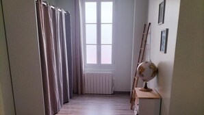 Una habitación con piso de madera, una cama, un radiador, un globo terráqueo y una ventana con cortinas.