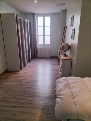A room with a wooden floor, a bed, a radiator, a globe, and a window with curtains. - "Le Bellem" – Rochefort, near the town center (Rochefort)