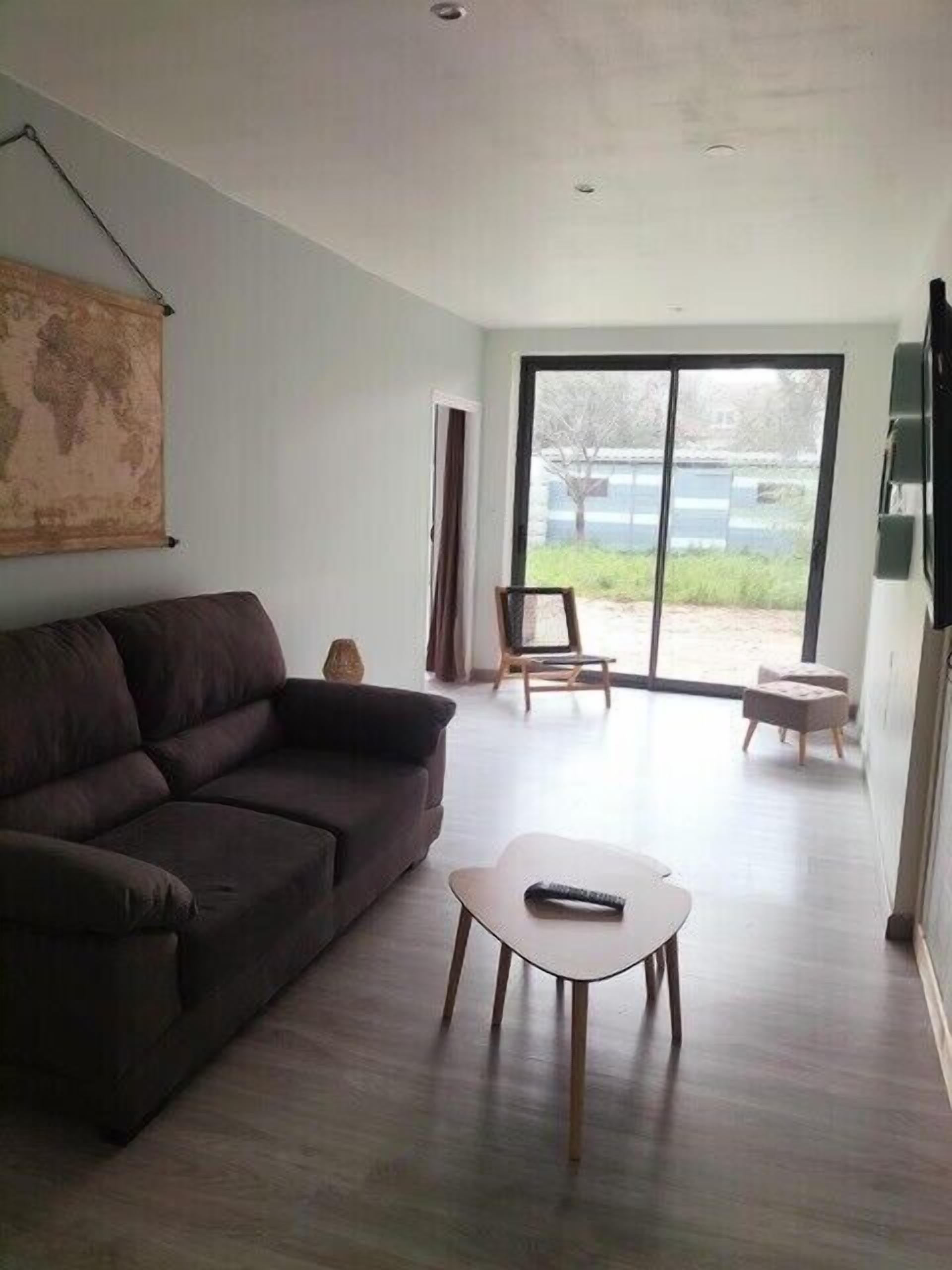 A living room with a sofa, a small table, and a large window with a view of the outdoors.