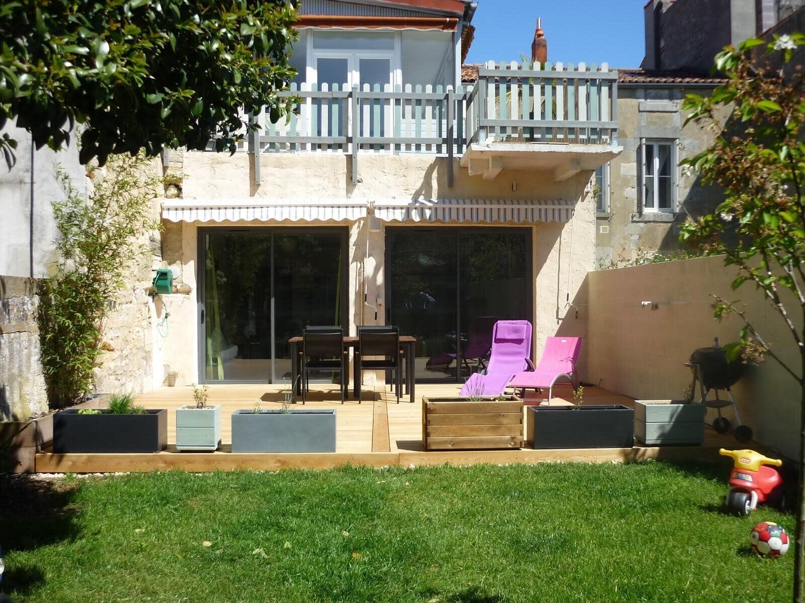 A backyard with a patio, a barbecue grill, and a red toy car.