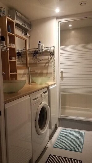 A compact bathroom with a washing machine, a sink with a large bowl, and a shower area. - "L'Hermione," Rochefort, close to the town center (Rochefort)