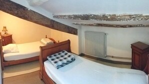 A bedroom with two single beds, a wooden headboard, a radiator, and a small wooden cabinet. - "L'Hermione," Rochefort, close to the town center (Rochefort)