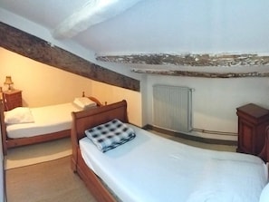 A bedroom with two single beds, a wooden headboard, a radiator, and a small wooden cabinet. - "L'Hermione," Rochefort, close to the town center (Rochefort)