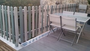 An outdoor patio with a table and chairs, a stone wall, and a wooden fence. - "L'Hermione," Rochefort, close to the town center (Rochefort)
