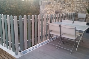 An outdoor patio with a table and chairs, a stone wall, and a wooden fence. - "L'Hermione," Rochefort, close to the town center (Rochefort)