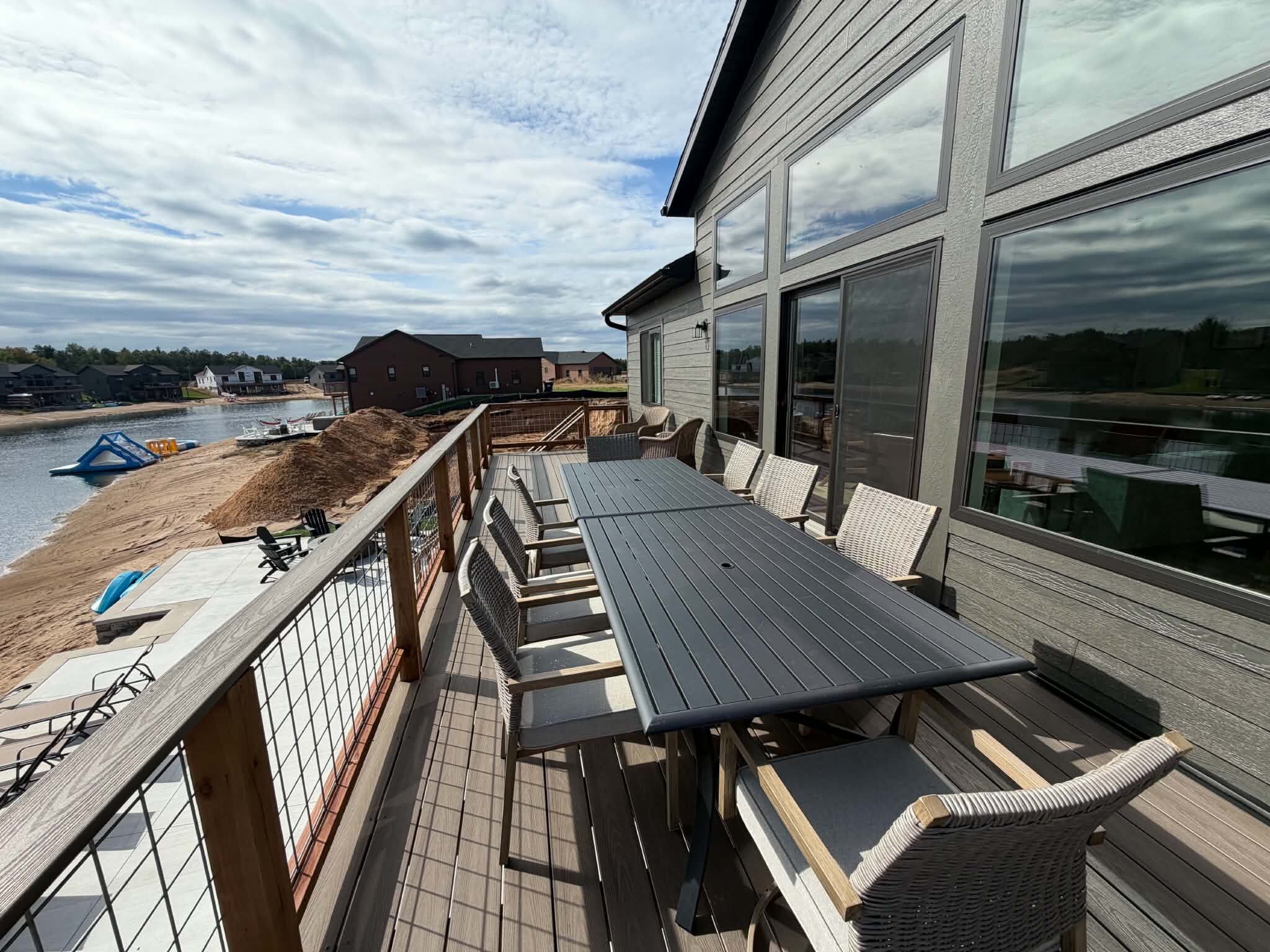 Una terraza con mobiliario exterior, vista al agua y un edificio con grandes ventanales.