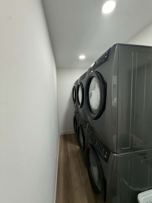 A laundry room with a row of stacked washing machines and dryers. - Sunset Lake Haven |Hot Tub | Inflatables | Arcade (New Lisbon)