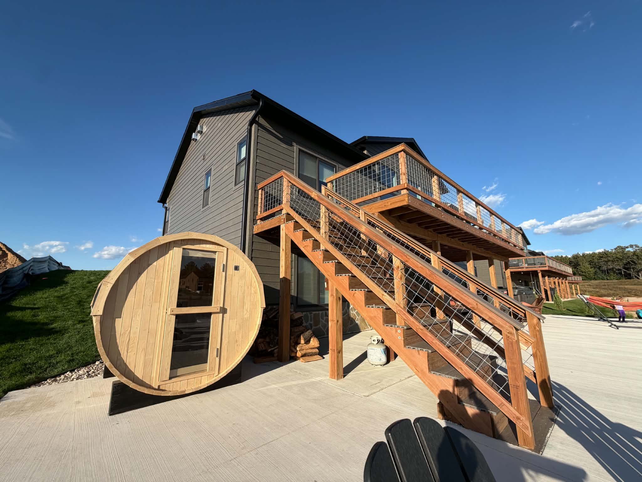 A house with a large wooden barrel, a staircase, and a deck.