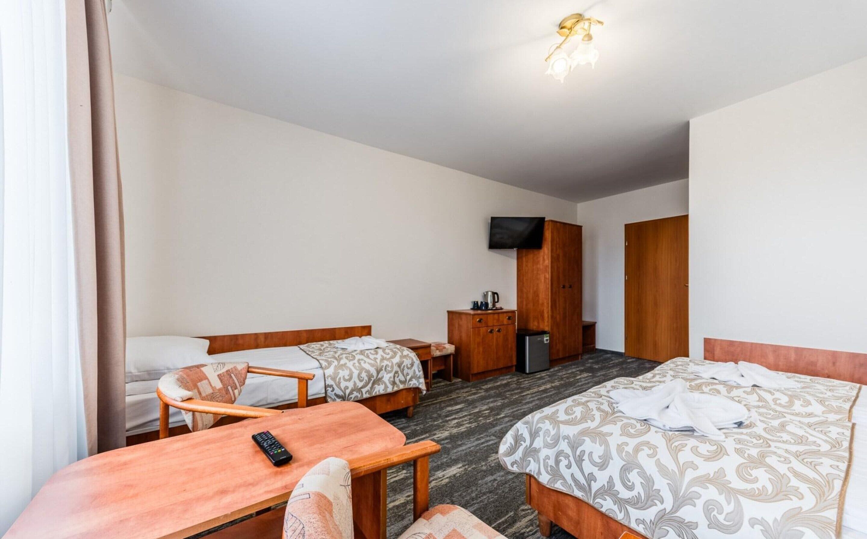A hotel room with two beds, a desk, a television, and a wardrobe.