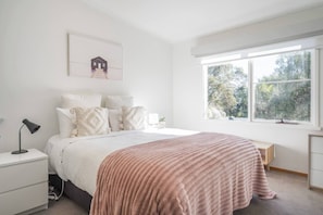 A bedroom with a bed, bedside tables, a lamp, a window with a view, and a picture on the wall. - Bayview Cottage Serene Escape between Beach and Bay (Blairgowrie)